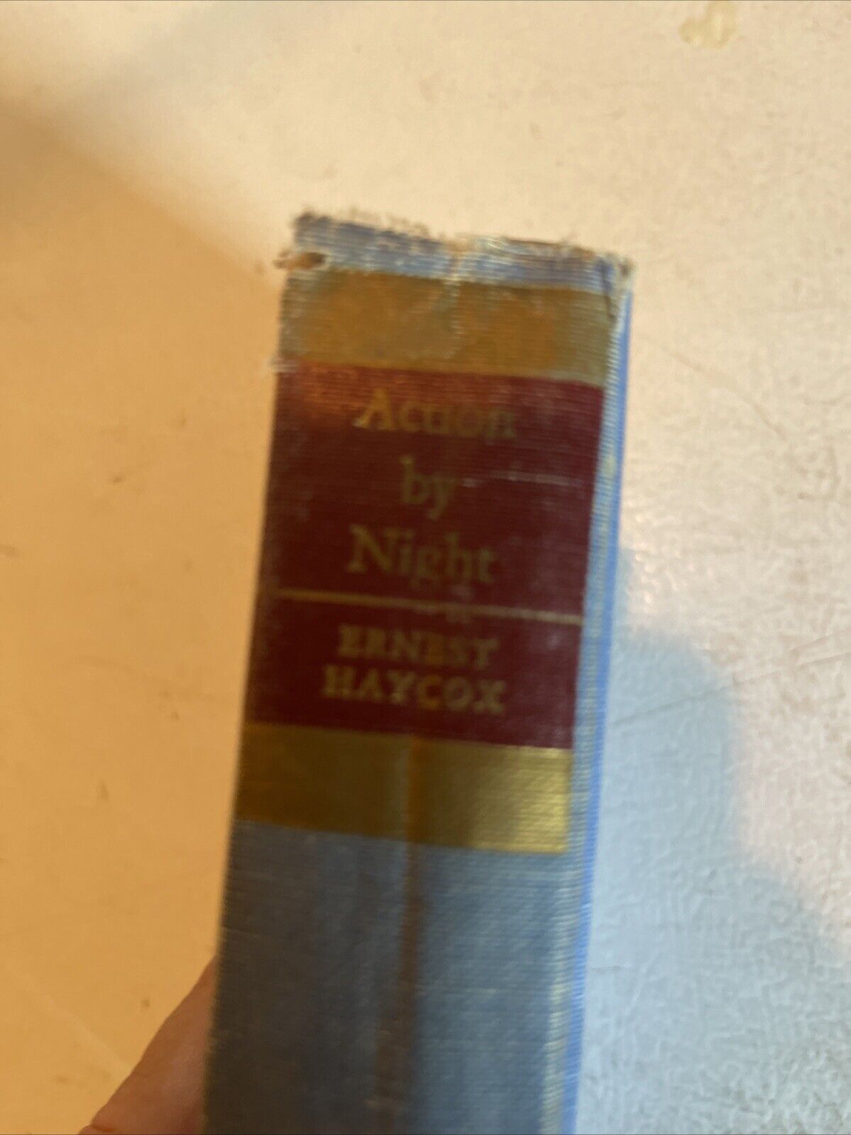 Spine of Action By Night hardcover book by Ernest Haycox with worn blue cover and gold and red label