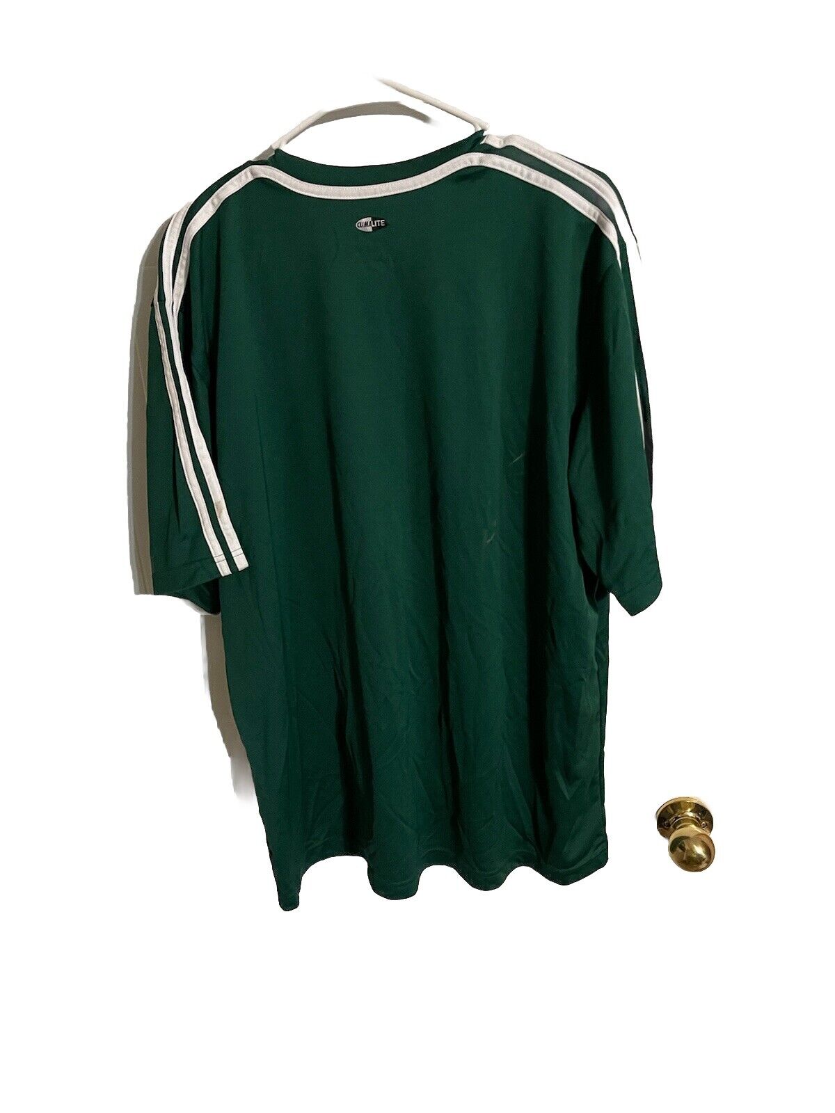 Green Adidas athletic shirt XL hanging on white hanger showing back with white stripes on sleeves