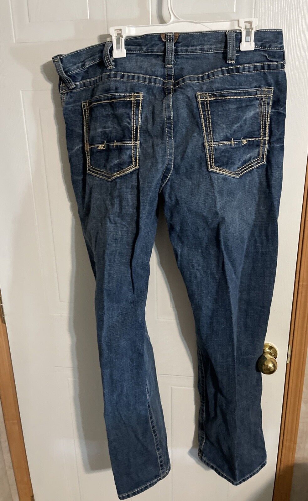 Ariat jeans 38x34 in dark blue denim with rear pockets and contrast stitching hanging on white hanger