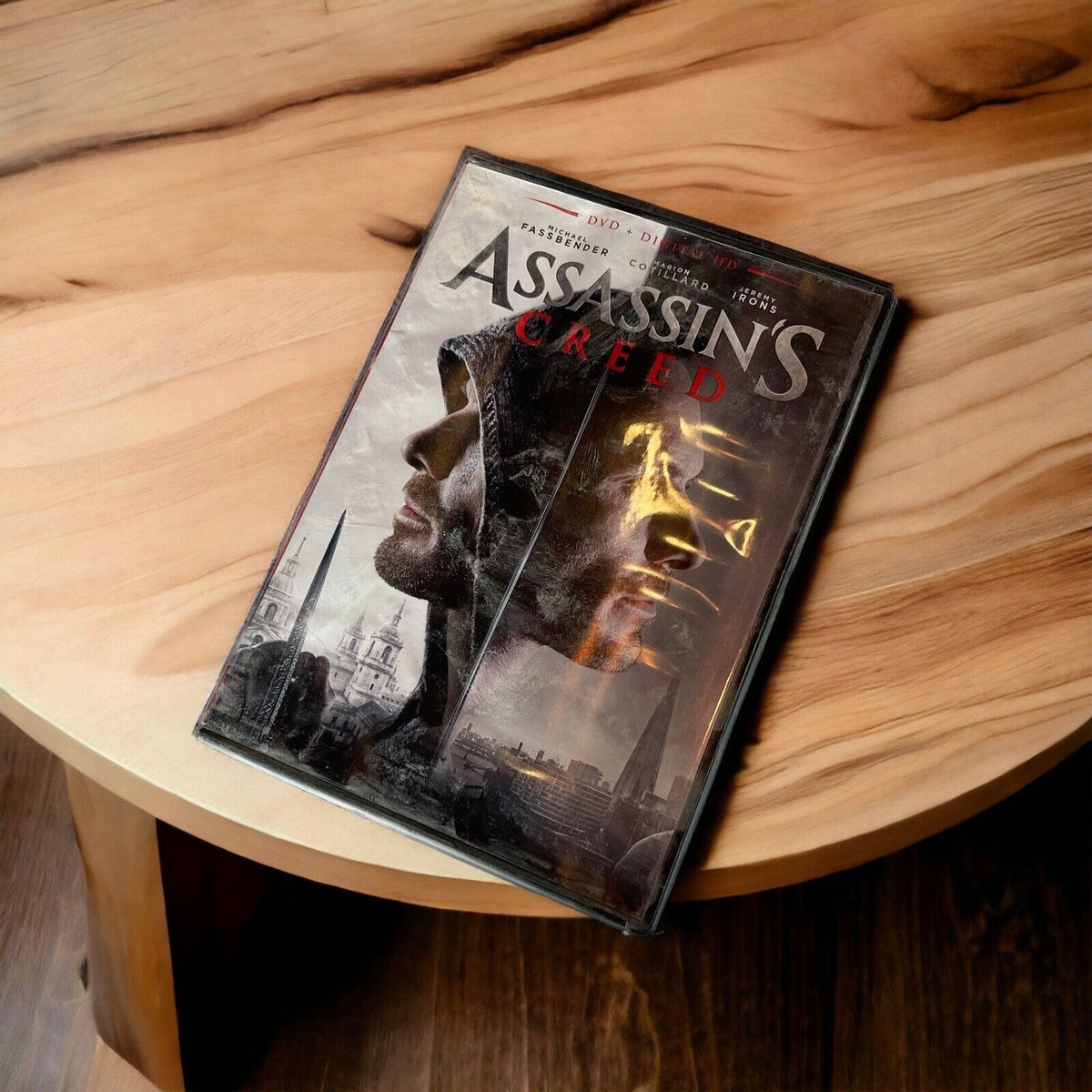 Assassin's Creed DVD 2016 movie case featuring dual profile faces on wooden table