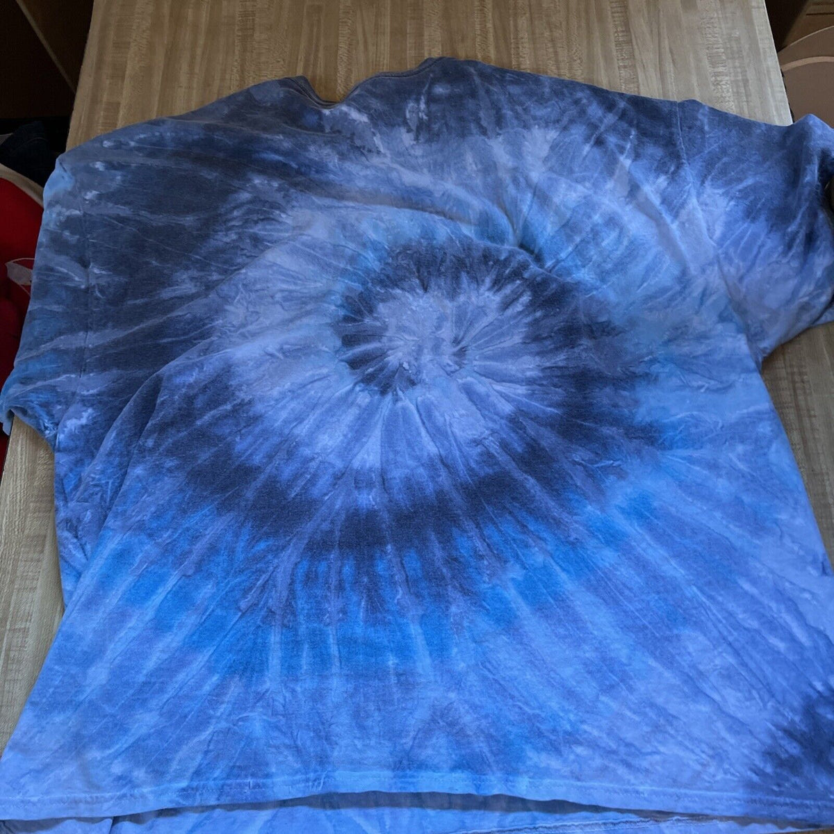 Blue and black tie-dye Knott's Berry Farm Peanuts T-shirt laid flat on a wooden surface