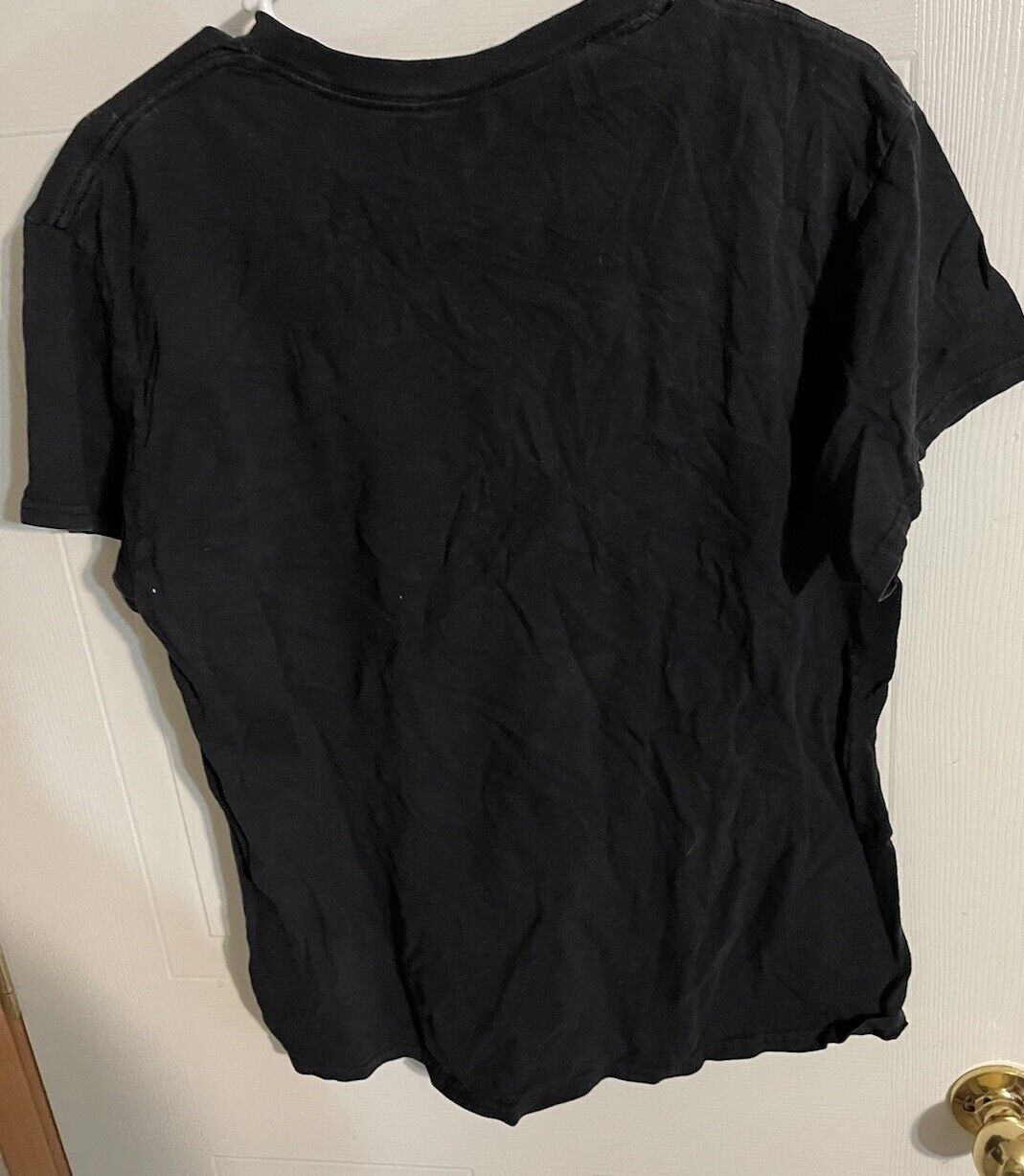 Black large anime t shirt displayed hanging on a white door with short sleeves