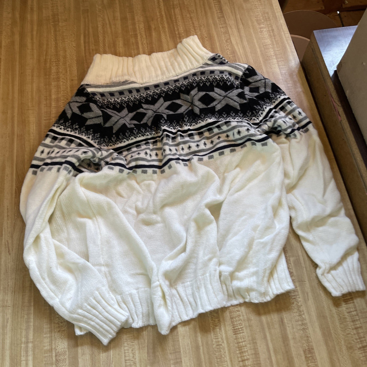 Zyfgfree large knit cardigan in white with black and gray geometric patterns on a wooden surface