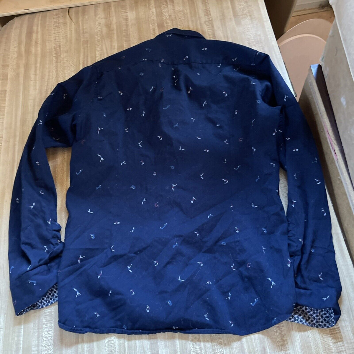 Navy blue Ted Baker men's button up shirt with subtle white prints laid flat on wooden surface