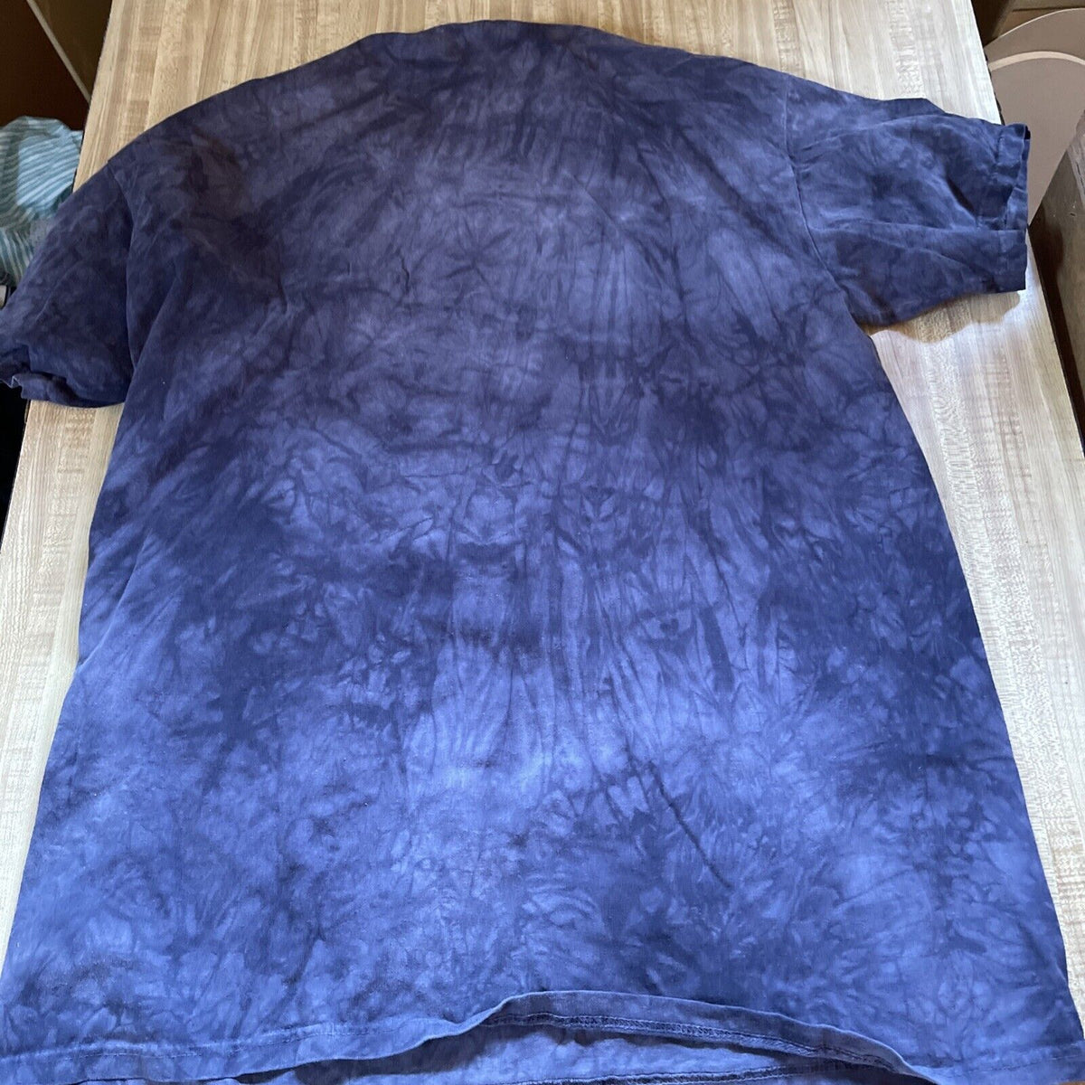 The Mountain eagle shirt in blue tie-dye design laid flat on wooden surface