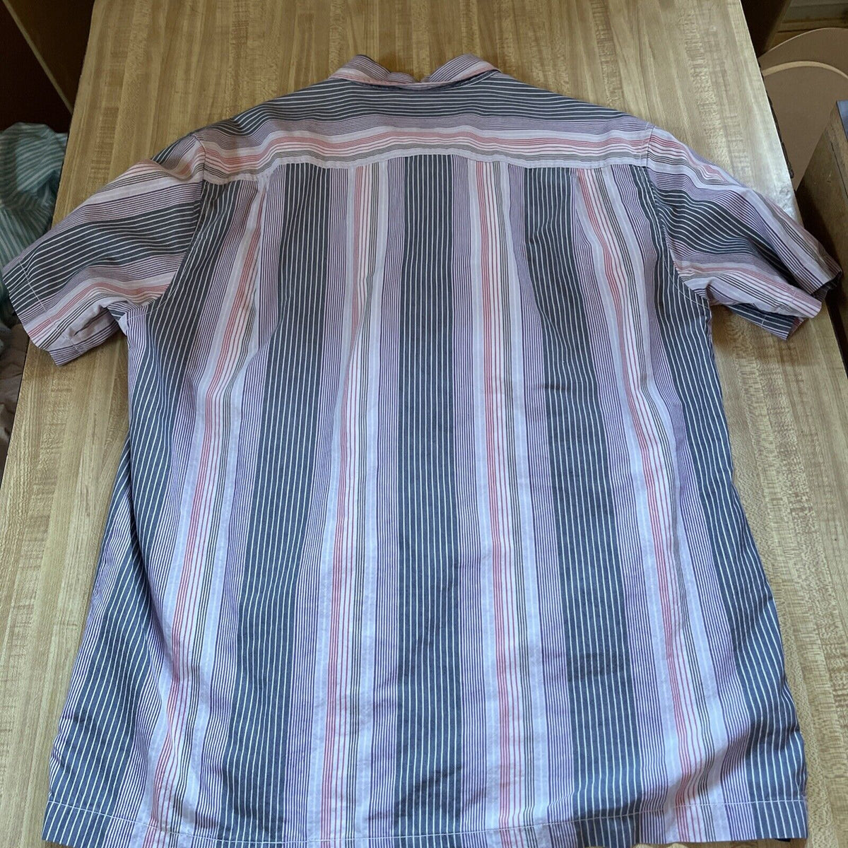 Tommy Bahama silk blend shirt with vertical stripes in blue and pink laid flat on wooden surface