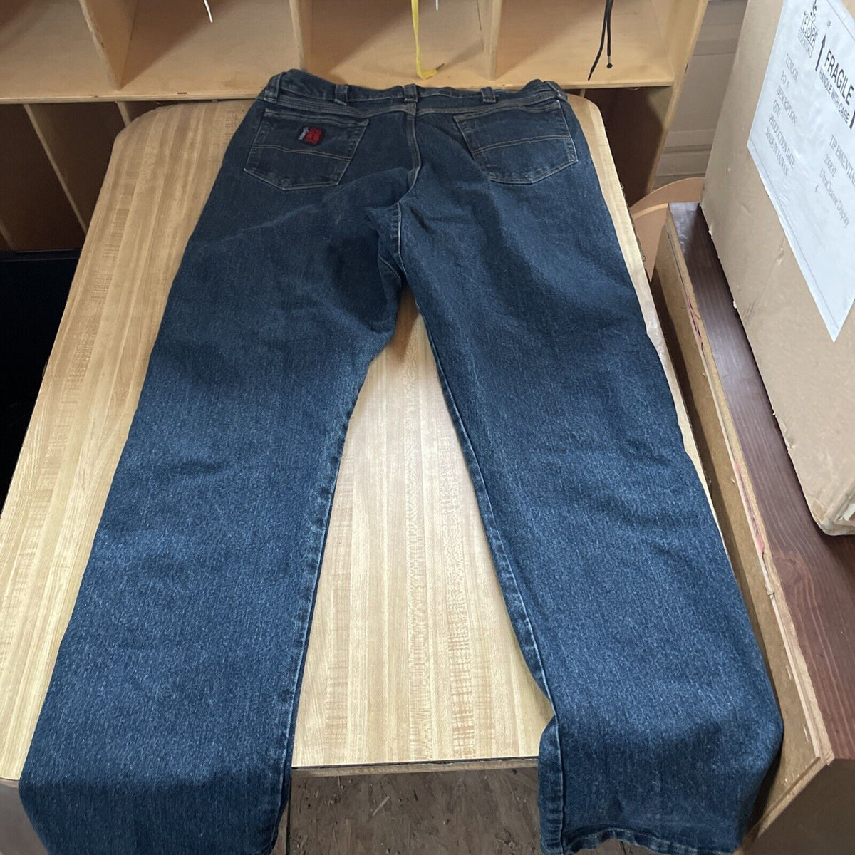 Wrangler Riggs work jeans 38x36 in dark blue denim laid flat on wooden surface
