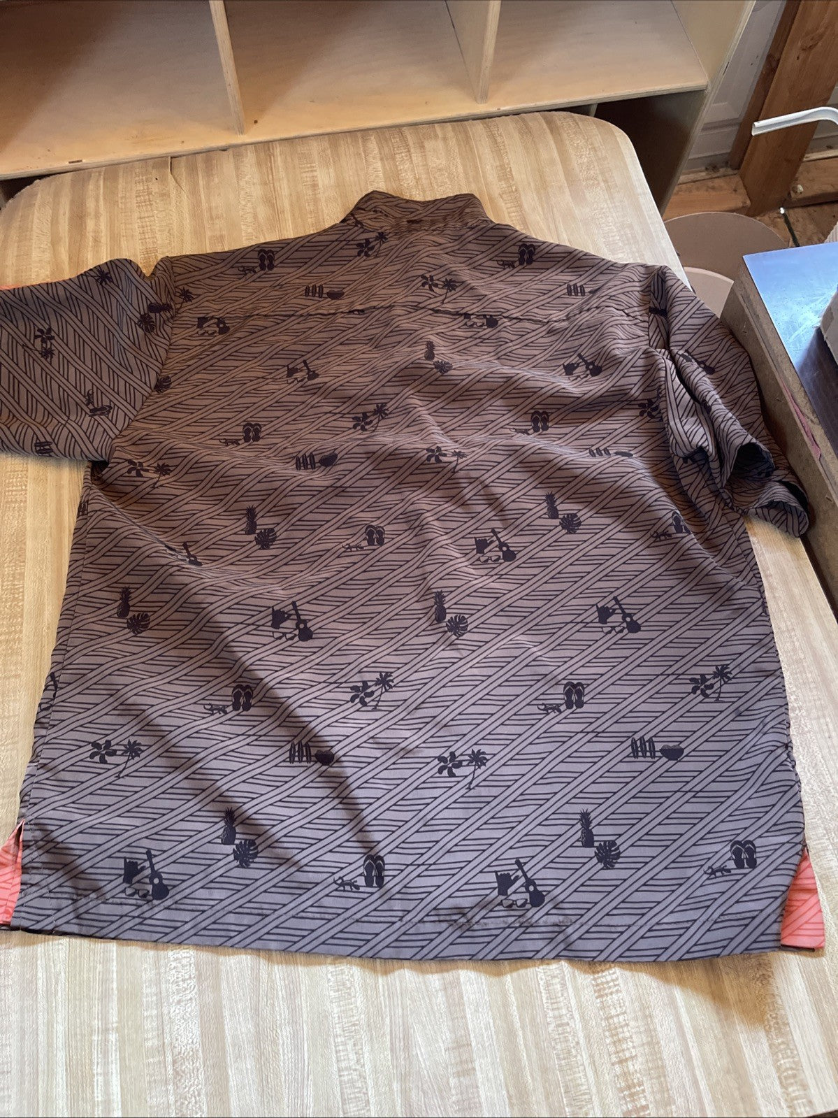 Zippy's Hawaiian shirt large brown with black geometric and tiki print laid flat on wooden surface