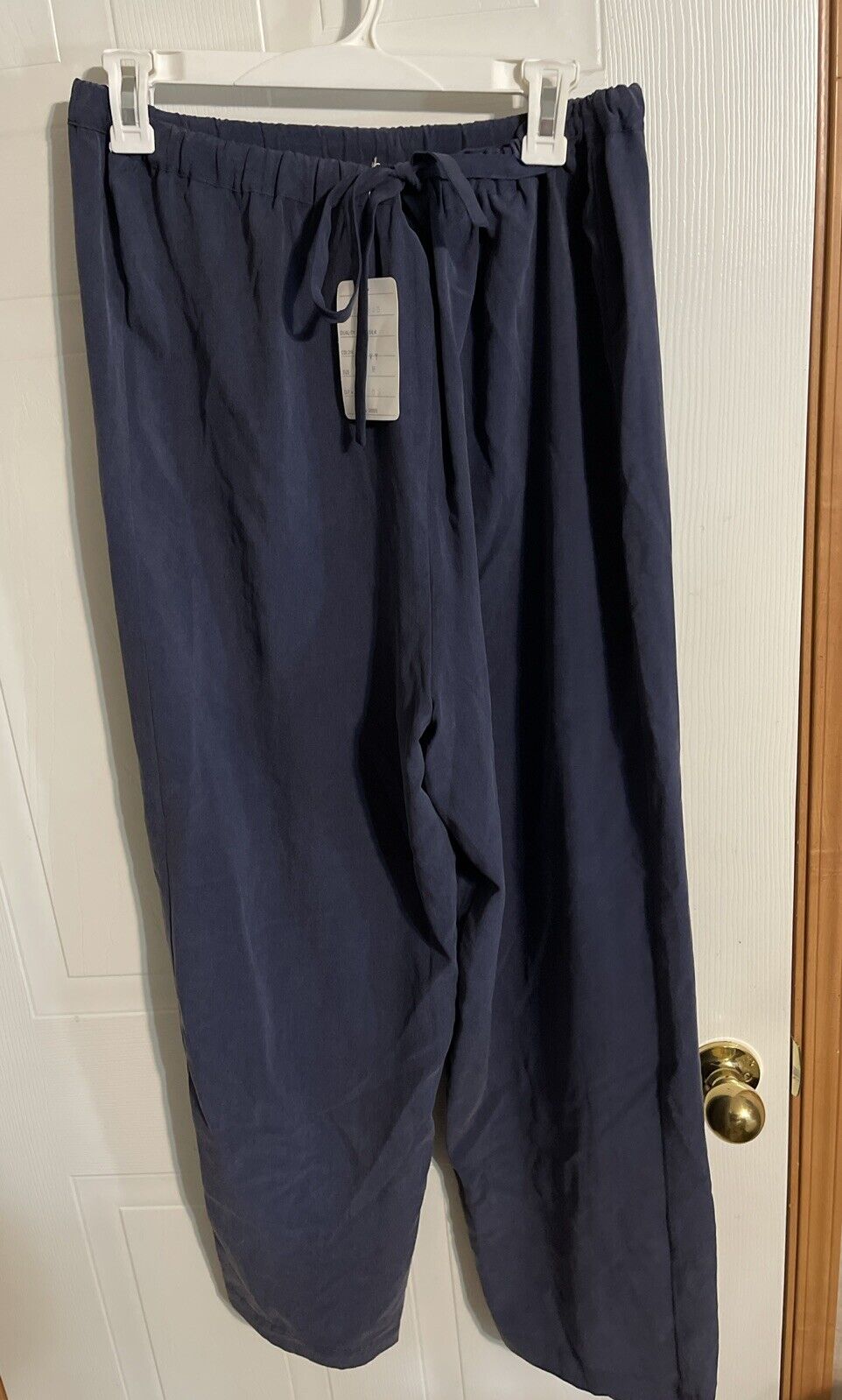 1010 Design silk loungewear navy blue drawstring pants hanging on white hanger