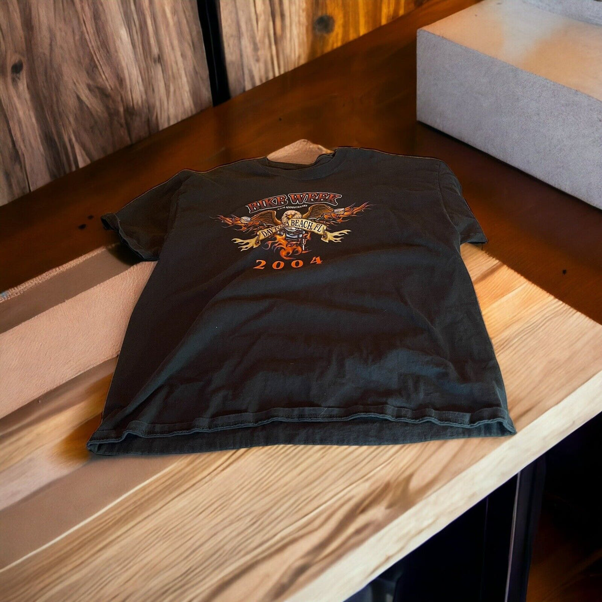 2004 Bike Week t shirt in black with flame graphic and event logo laid flat on wooden table