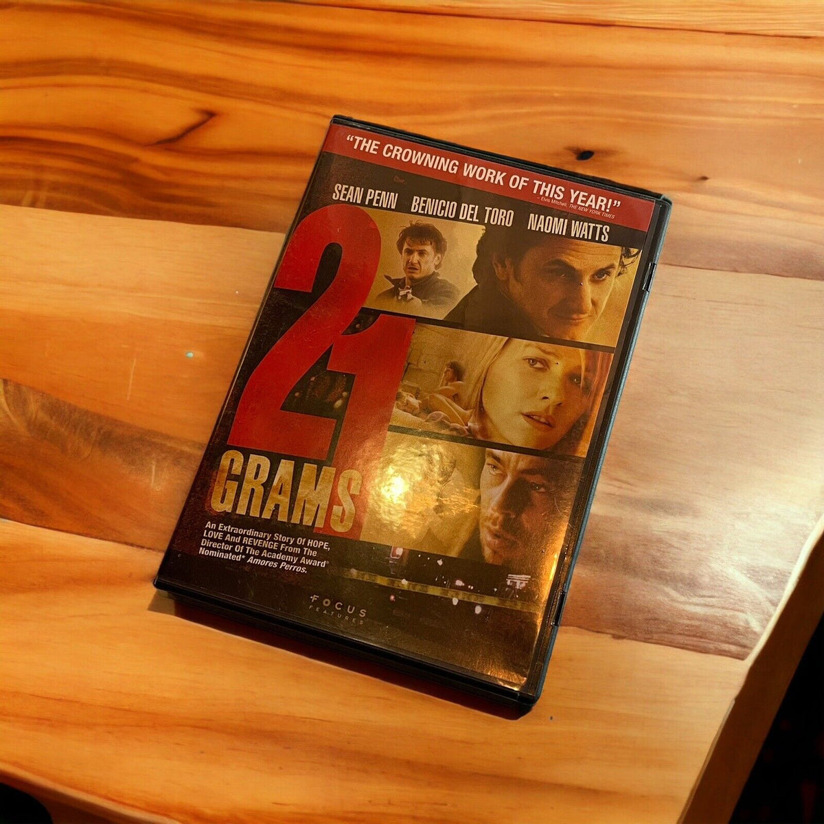 21 Grams DVD movie featuring Sean Penn, Benicio Del Toro, and Naomi Watts on wood surface