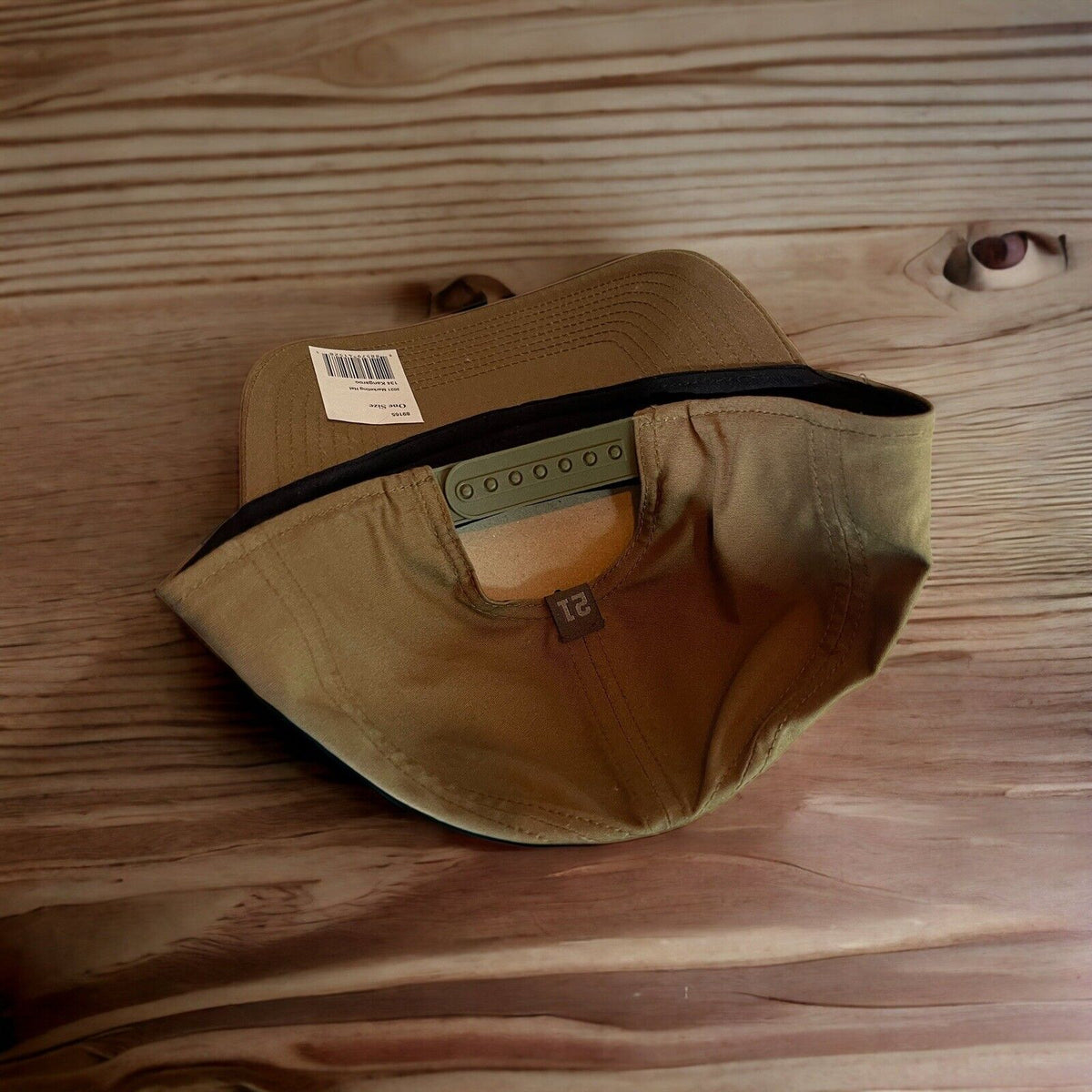 Tan 5.11 Tactical SnapBack hat with adjustable strap and black inner lining on wooden surface