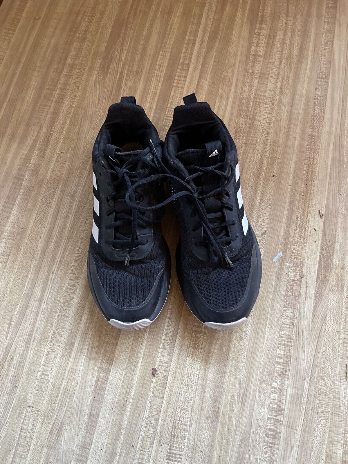 Pair of adidas lightmotion size 11 black running shoes with white stripes on wood floor