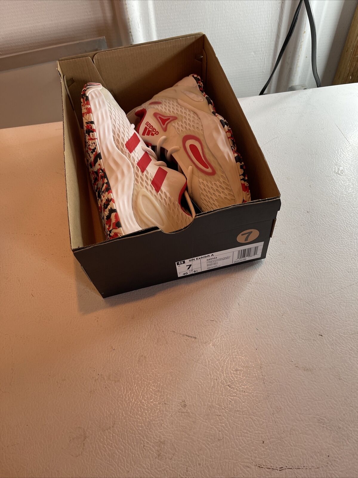 Adidas SM Exhibit A Team USA sneakers in white and red inside an open black shoe box on a white surface