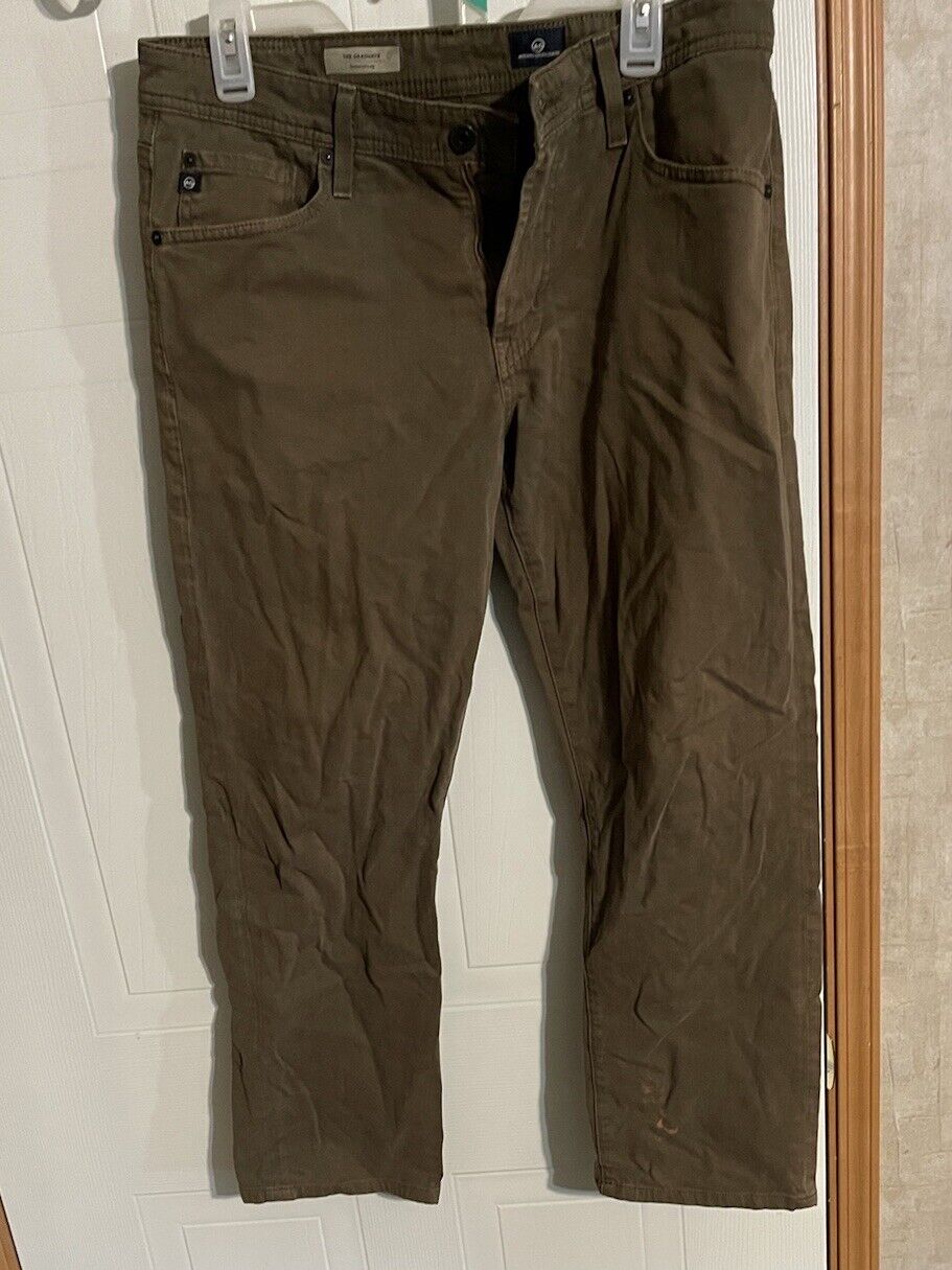 AG The Graduate men's jeans in brown color hanging on a hanger with a classic five-pocket design