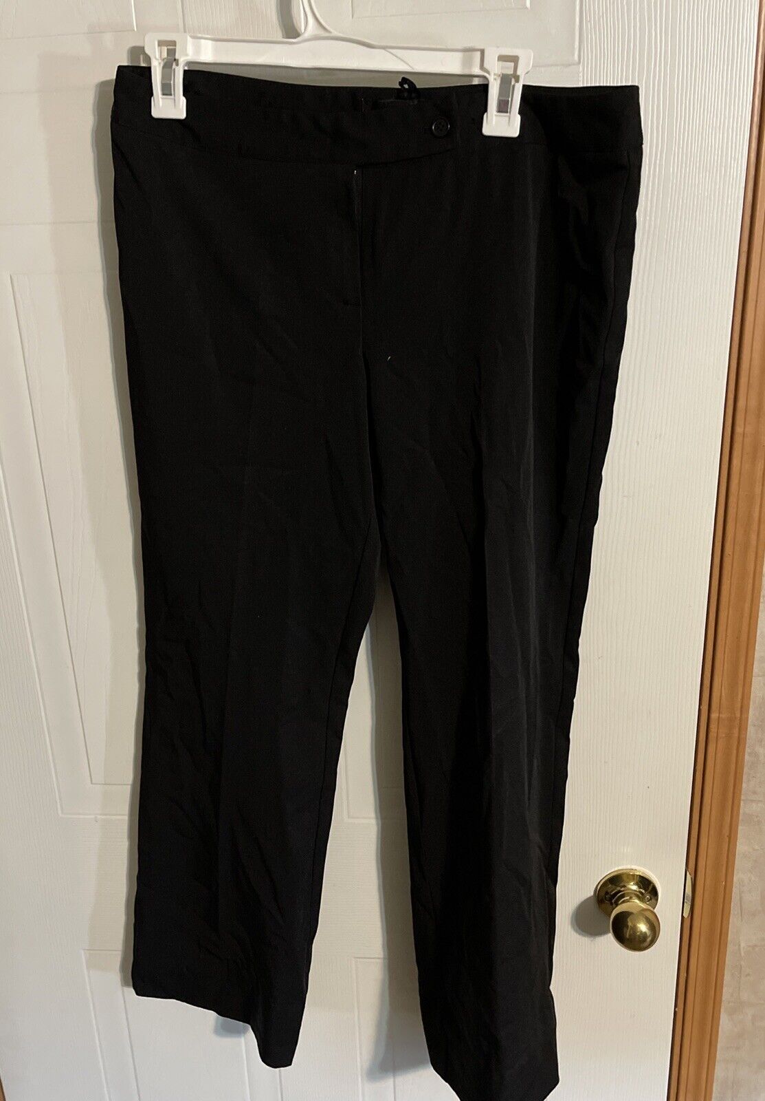 Alyn Paige black pants size 8 hanging on white hanger against a white door