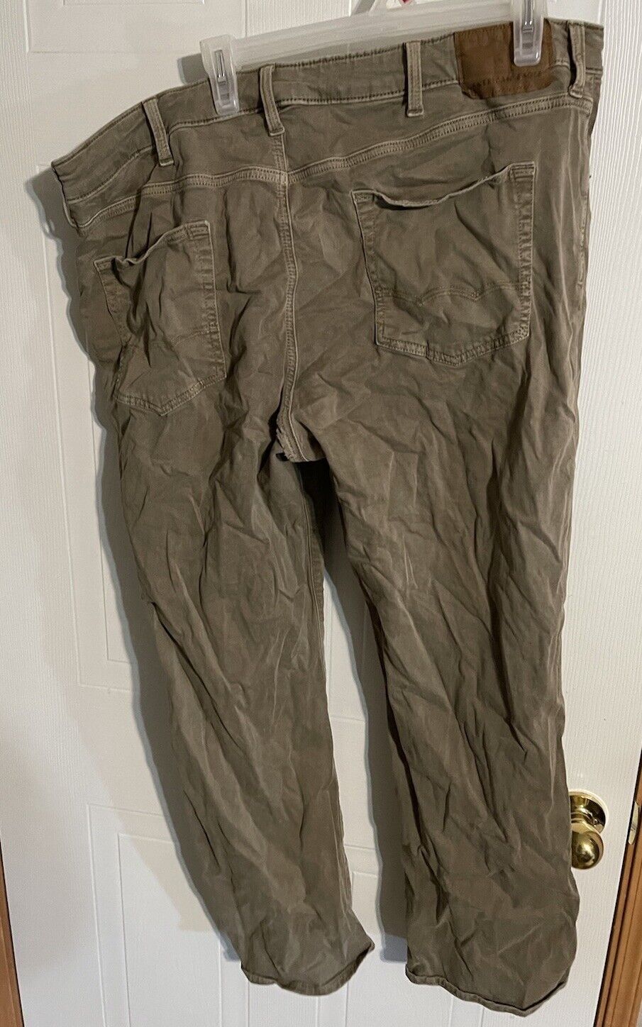 American Eagle flex pants 40x32 in olive green hanging on door with back pockets visible