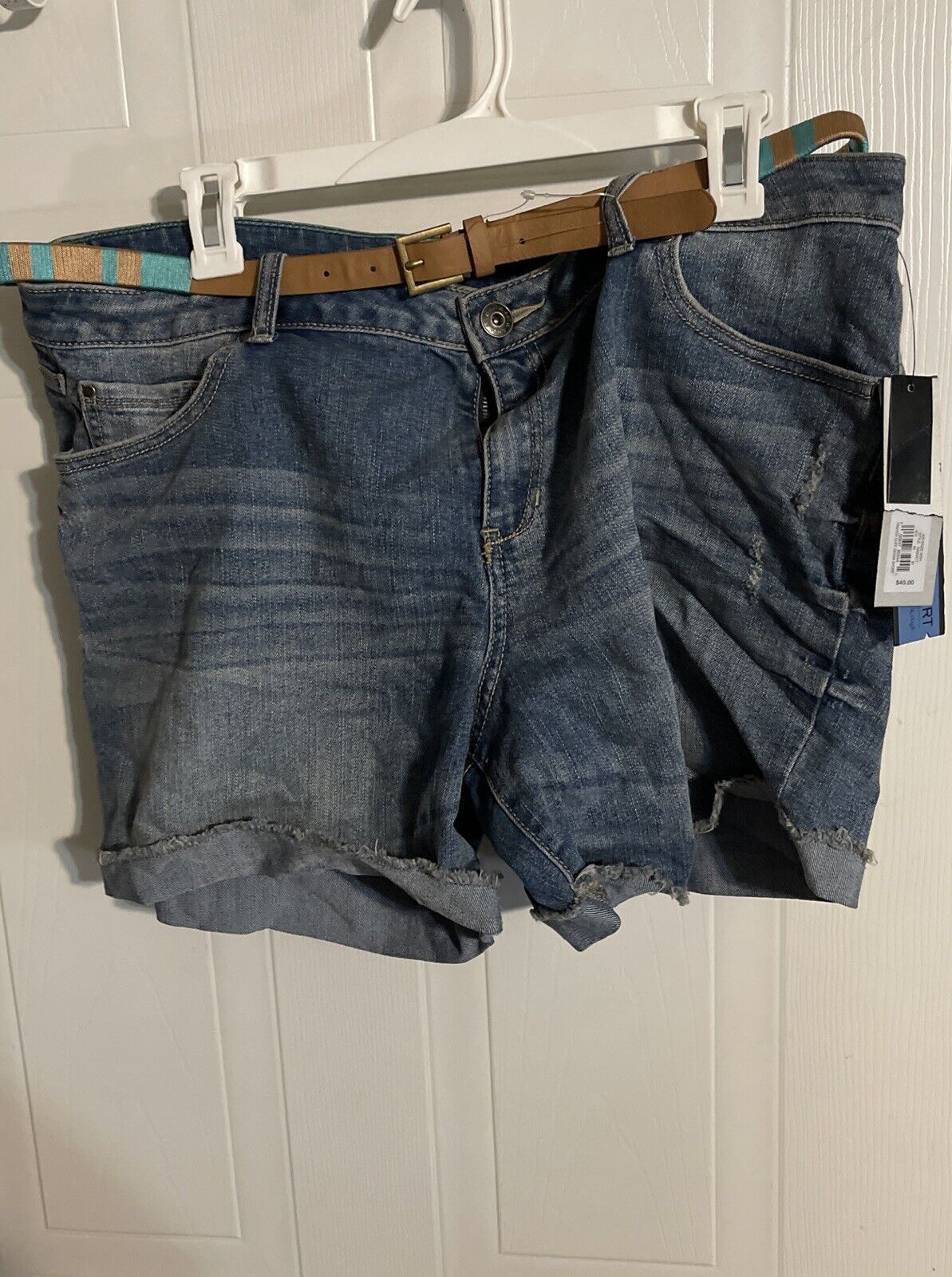 Apt 9 denim shorts in blue with a brown belt hanging on a white hanger