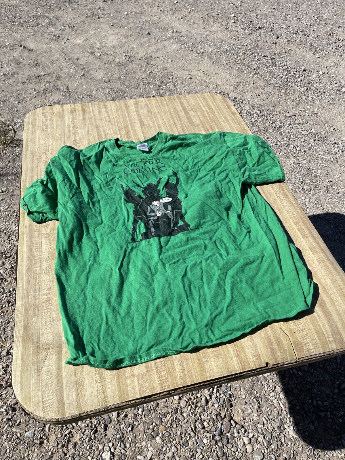 Green Archer graphic t-shirt 2XL laid flat on wooden table outdoors on gravel surface