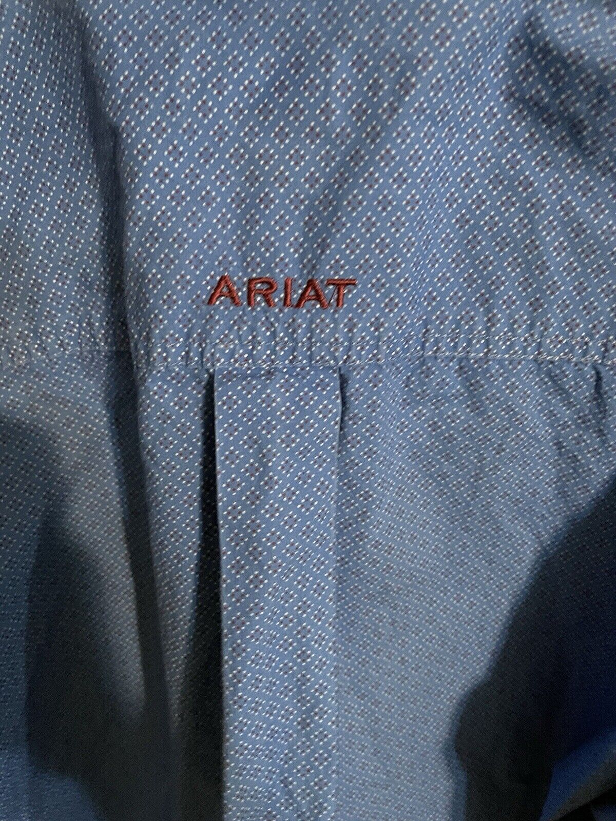 Close-up of Ariat blue button down shirt fabric with embroidered Ariat logo