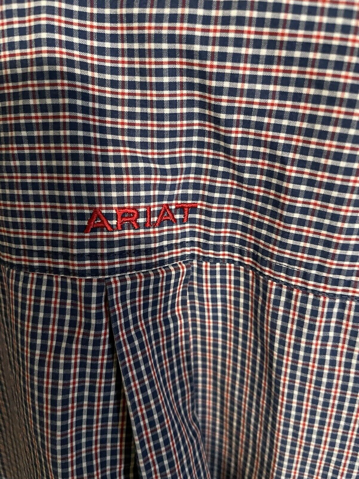 Close-up of navy and red plaid Ariat Pro Series shirt with embroidered Ariat logo