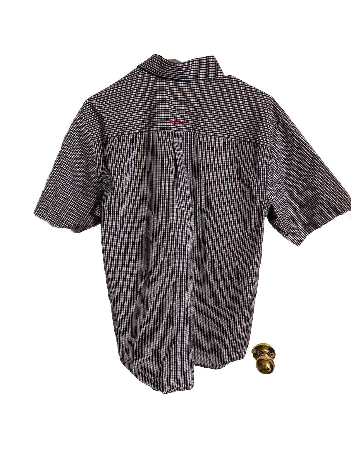 Back view of Ariat Pro Series shirt with short sleeves and checkered pattern hanging on a door