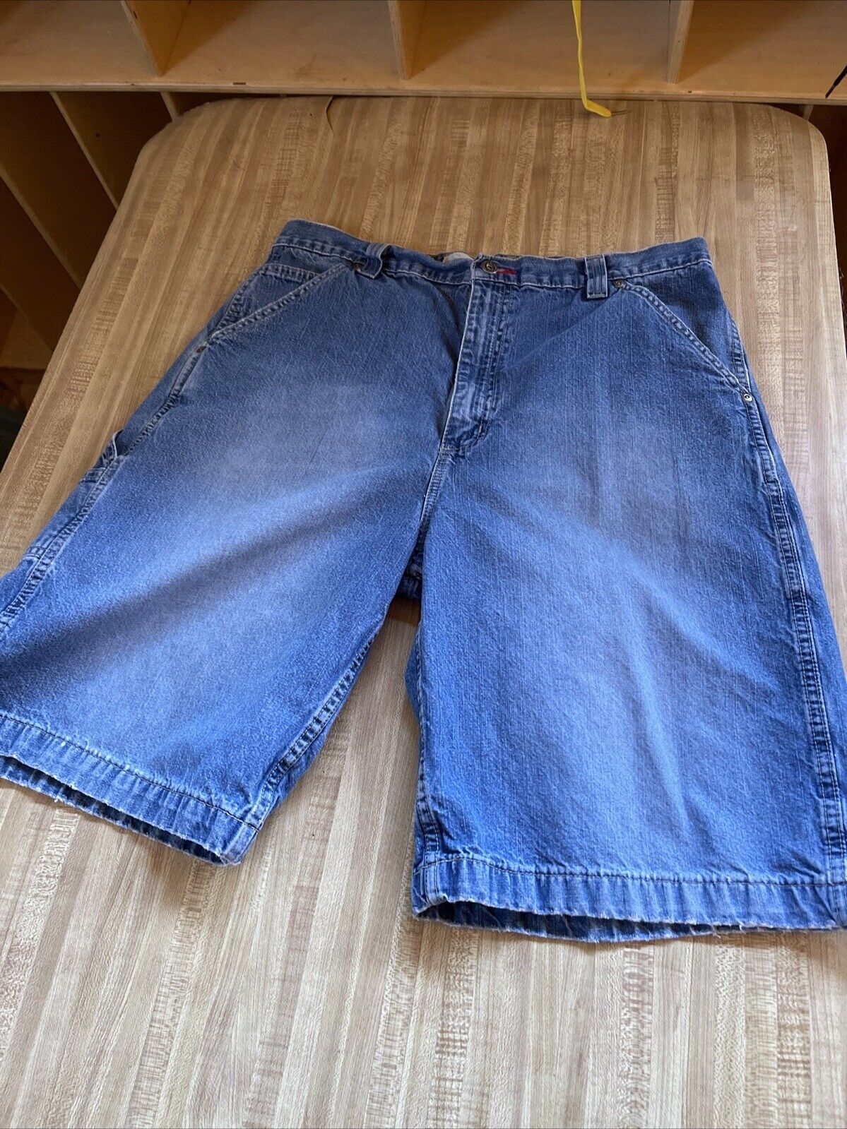 Blue denim Arizona carpenter jorts 36 with classic five-pocket design laid flat on wooden surface