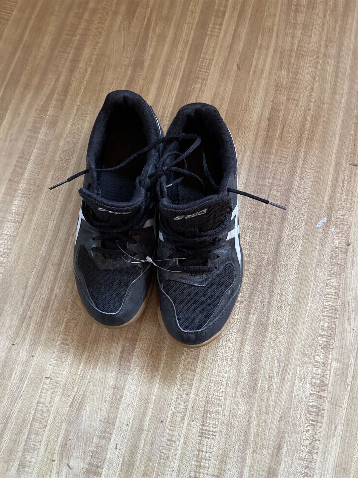 Pair of black ASICS Gel Rocket size 9.5 basketball shoes on wooden floor