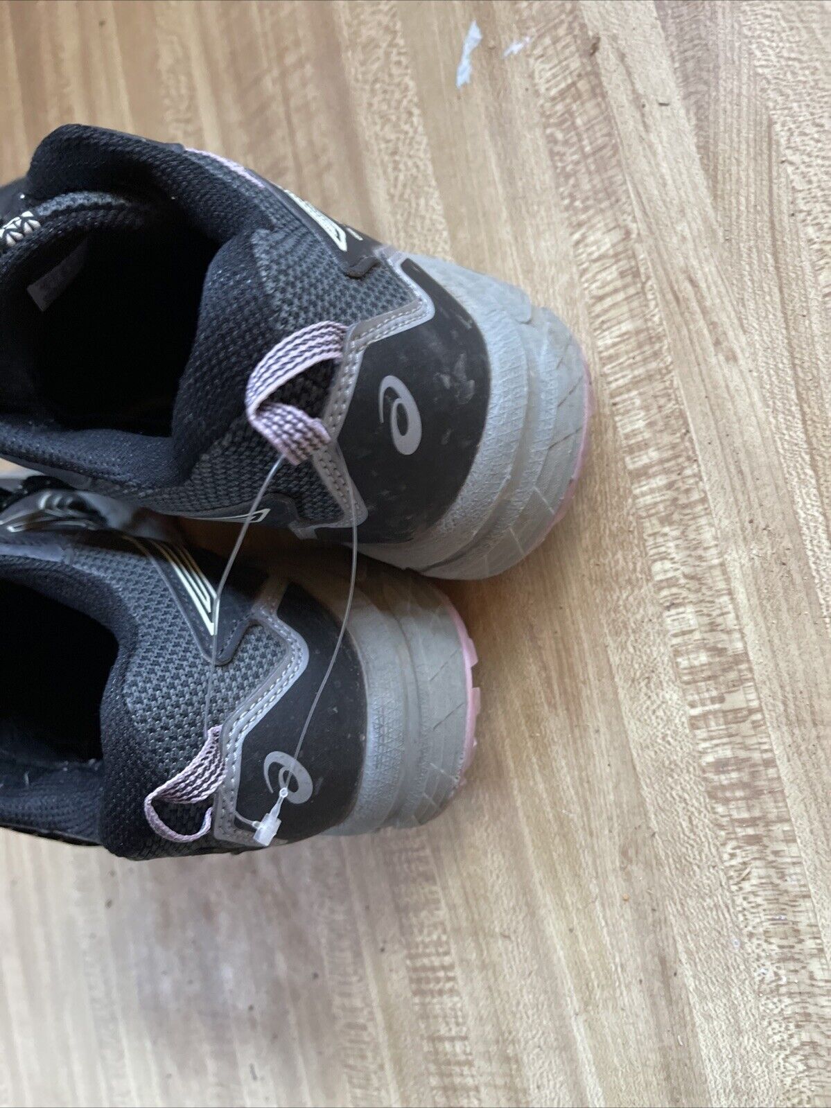 ASICS Gel Venture 8 women’s wide black running shoes with gray and pink accents on wooden floor