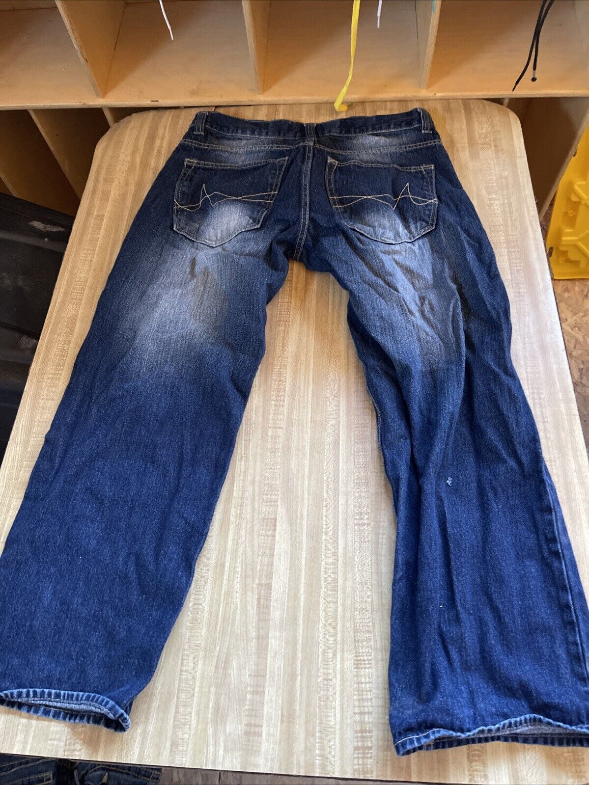 Dark blue Avirex jeans 34x30 with back pockets featuring stitched design laid flat on wooden surface
