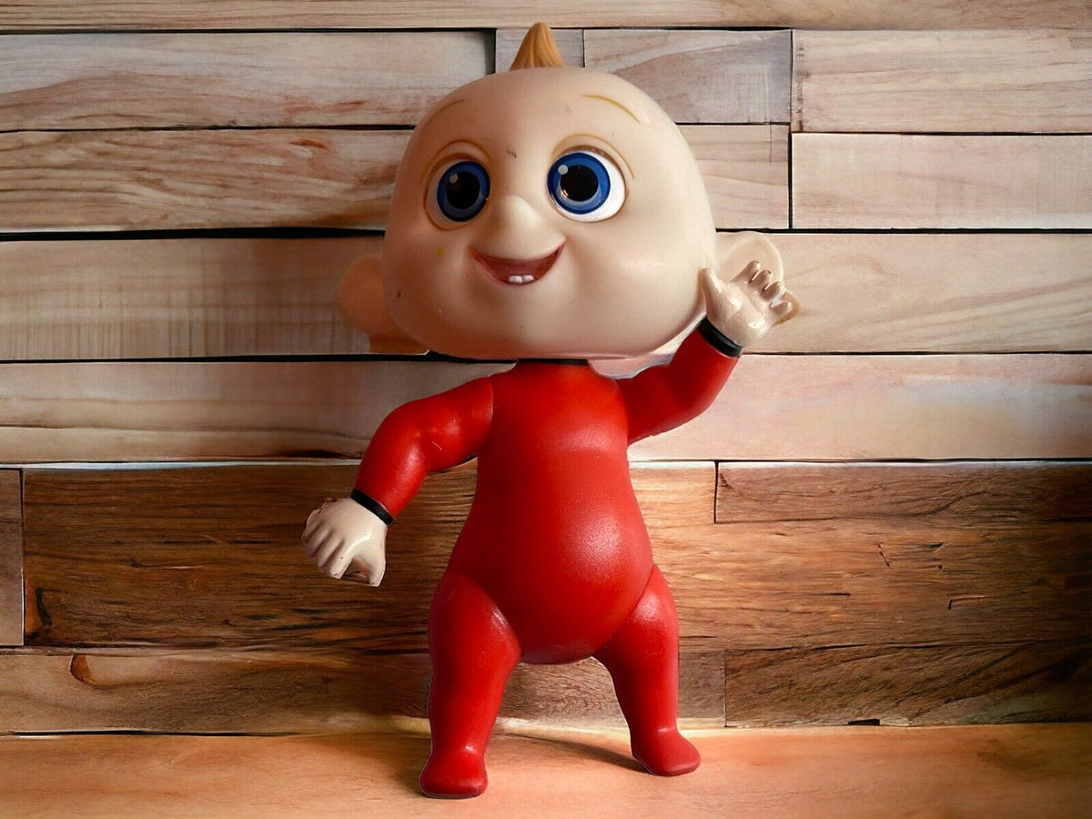Baby Jack doll with large blue eyes and red outfit standing on wooden surface