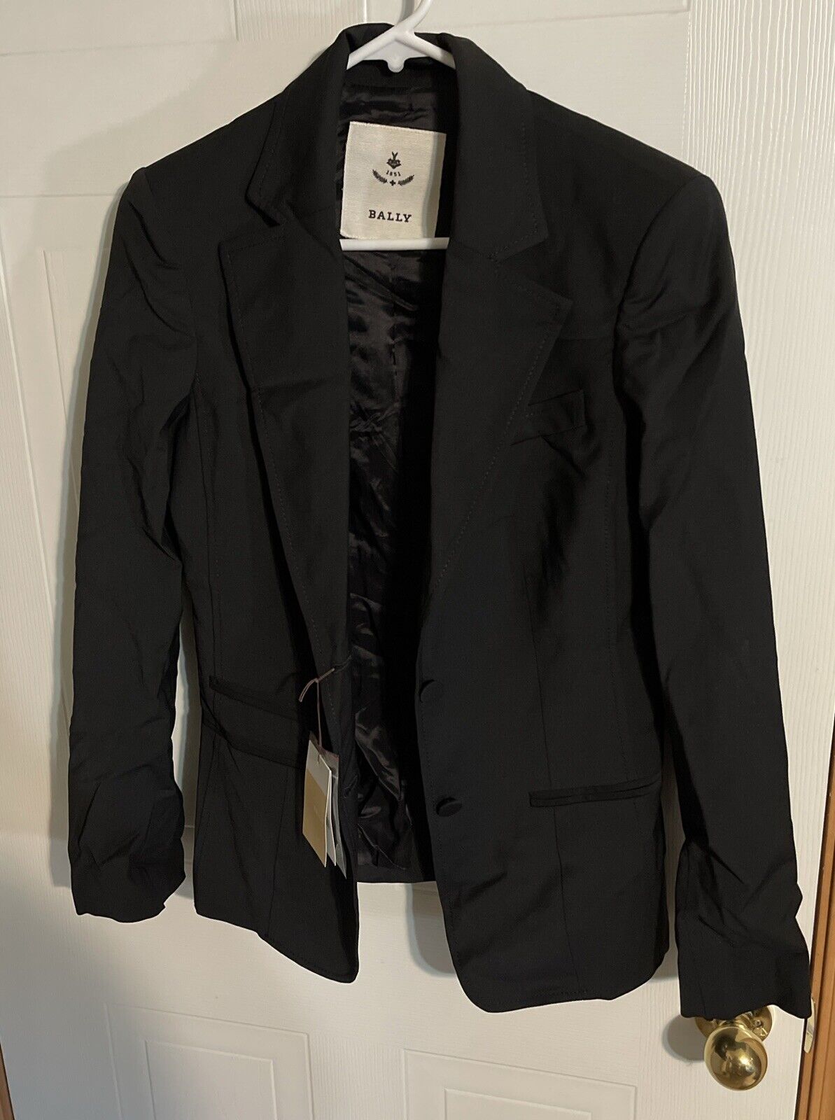 Bally black suit pants size 10 paired with a black blazer hanging on a white hanger