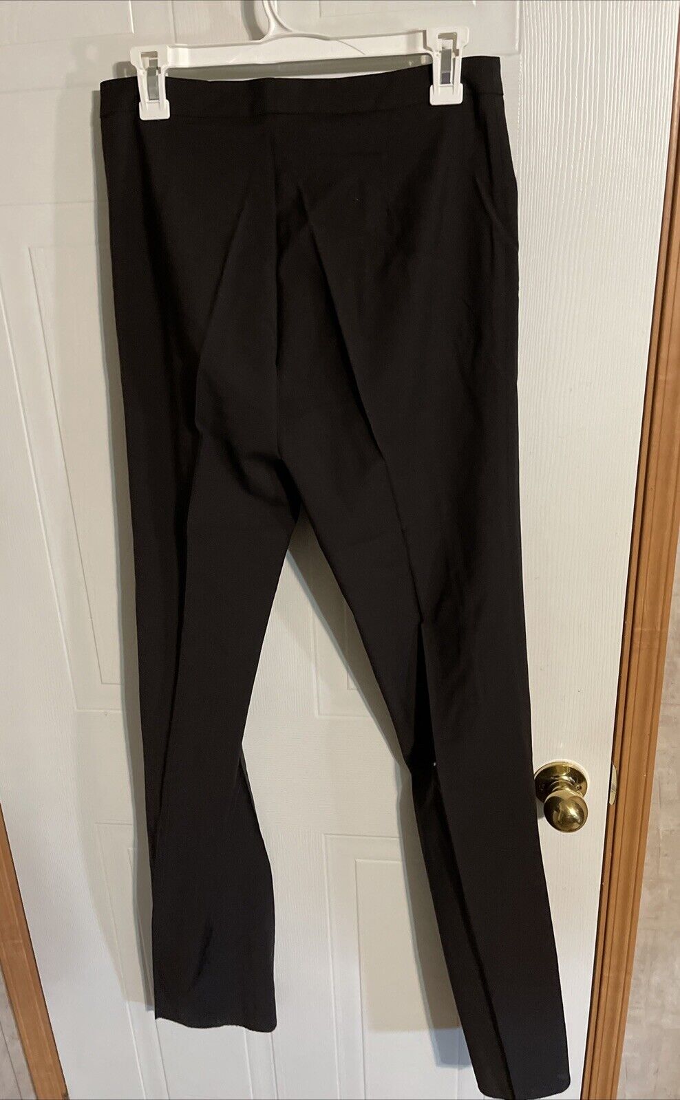 Black Bally dress pants for women hanging on a white door with a hanger