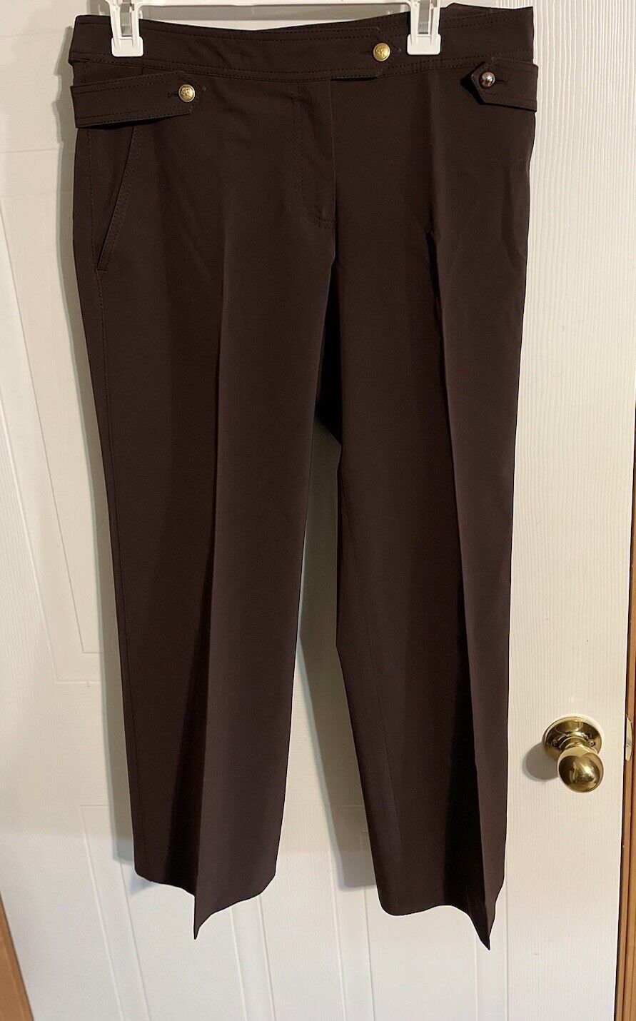 Bally women's brown dress pants with buttoned side pockets hanging on white hanger
