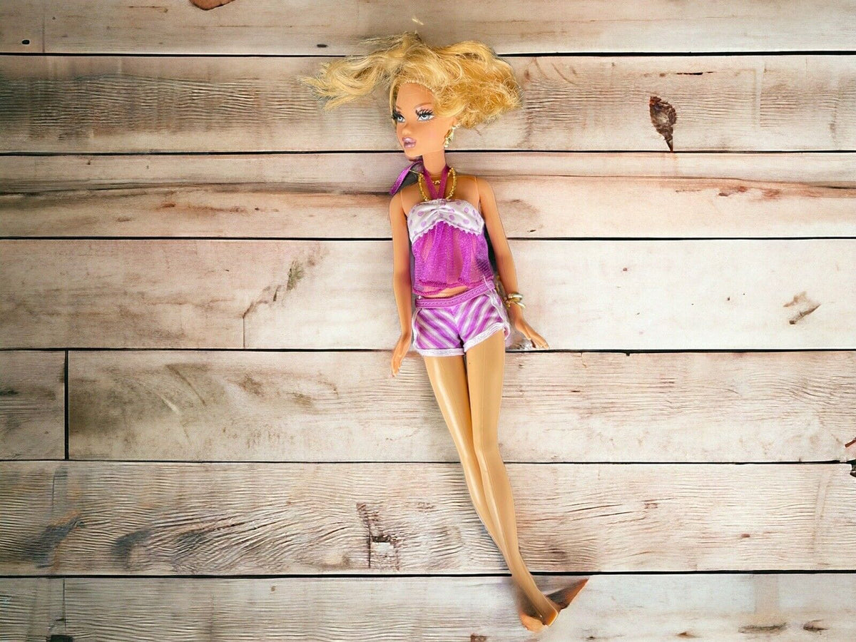 Classic Barbie doll wearing purple and white outfit with blonde hair lying on wooden floor