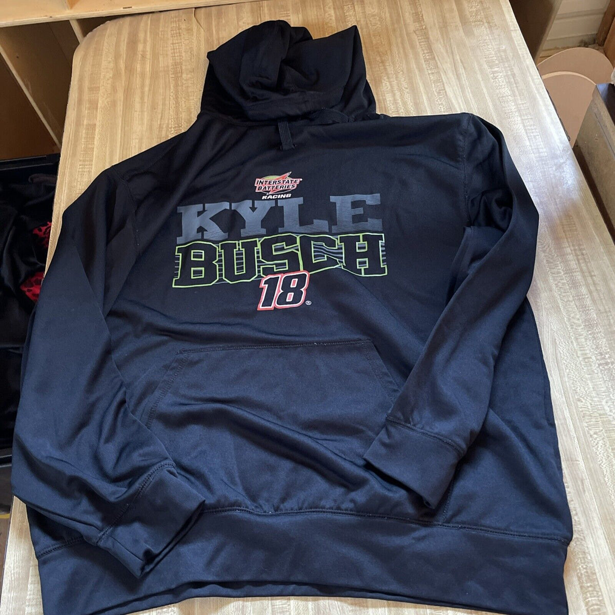 Black Kyle Busch NASCAR hoodie with 18 logo and front pocket laid flat on wooden table