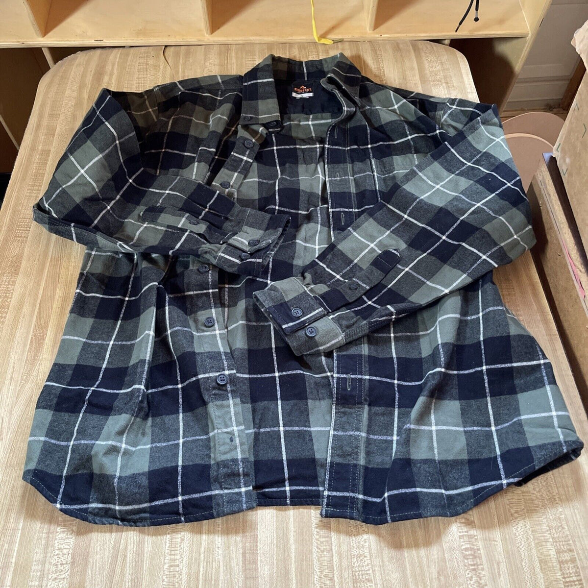 Men's plaid flannel shirt in black and grey check pattern by 1118 Emporium laid flat on a wooden surface