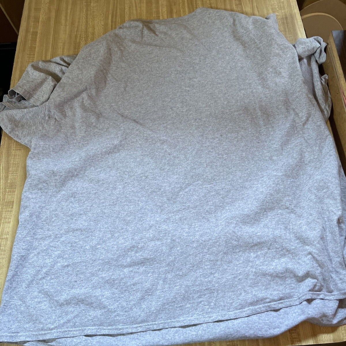 Grey plain fabric Nintendo controller t shirt 4XL laid flat on wooden surface