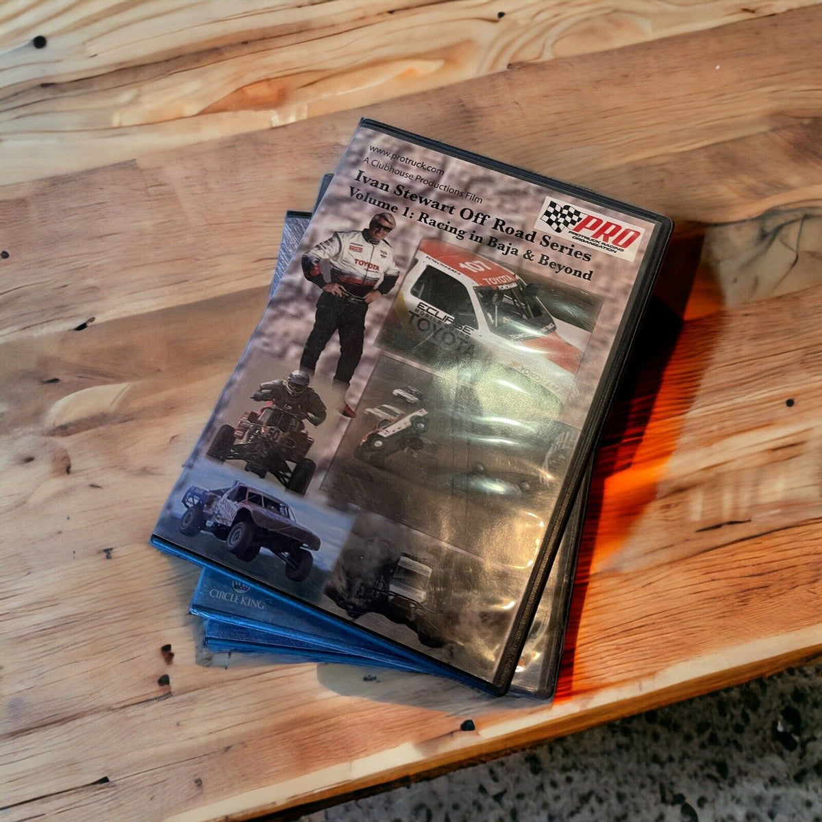 Stack of monster truck dvd collection cases featuring off-road racing and trucks on wooden table