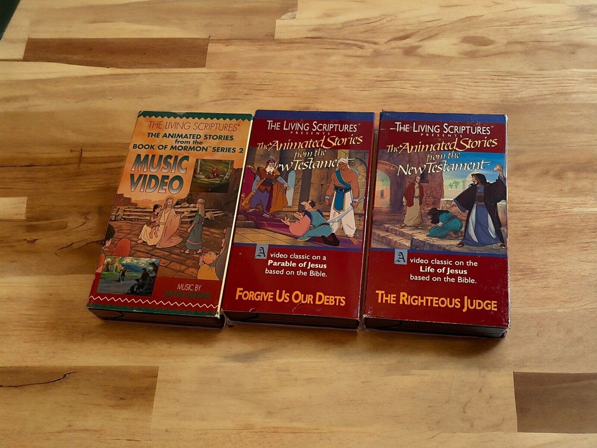 Religious animated VHS lot featuring The Living Scriptures animated stories on wooden surface