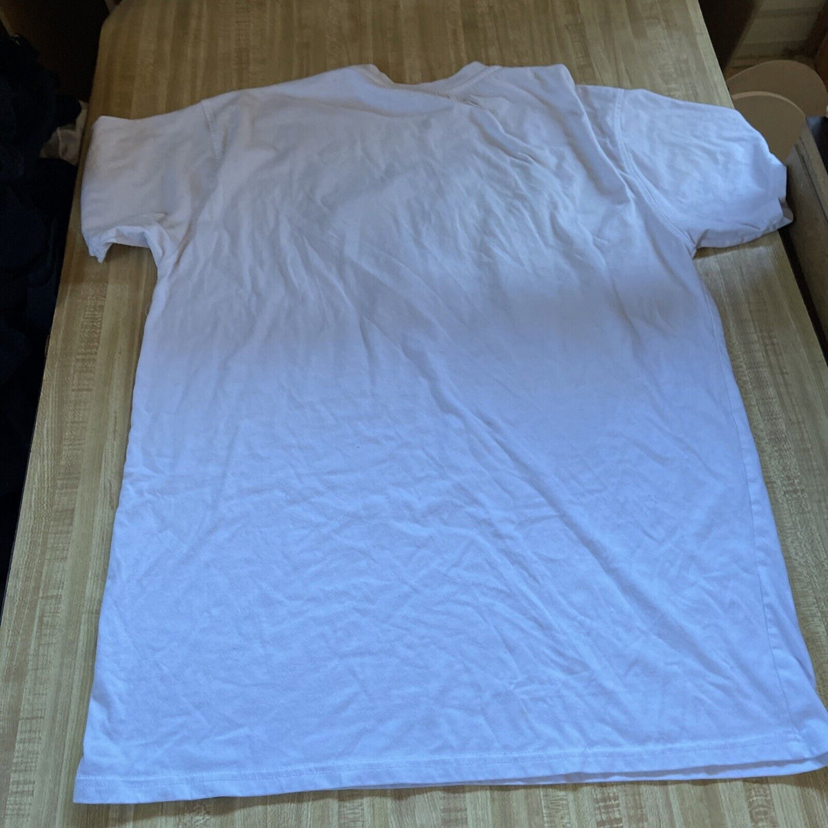 Plain white screenshot t shirt for men laid flat on a wooden surface showing back side