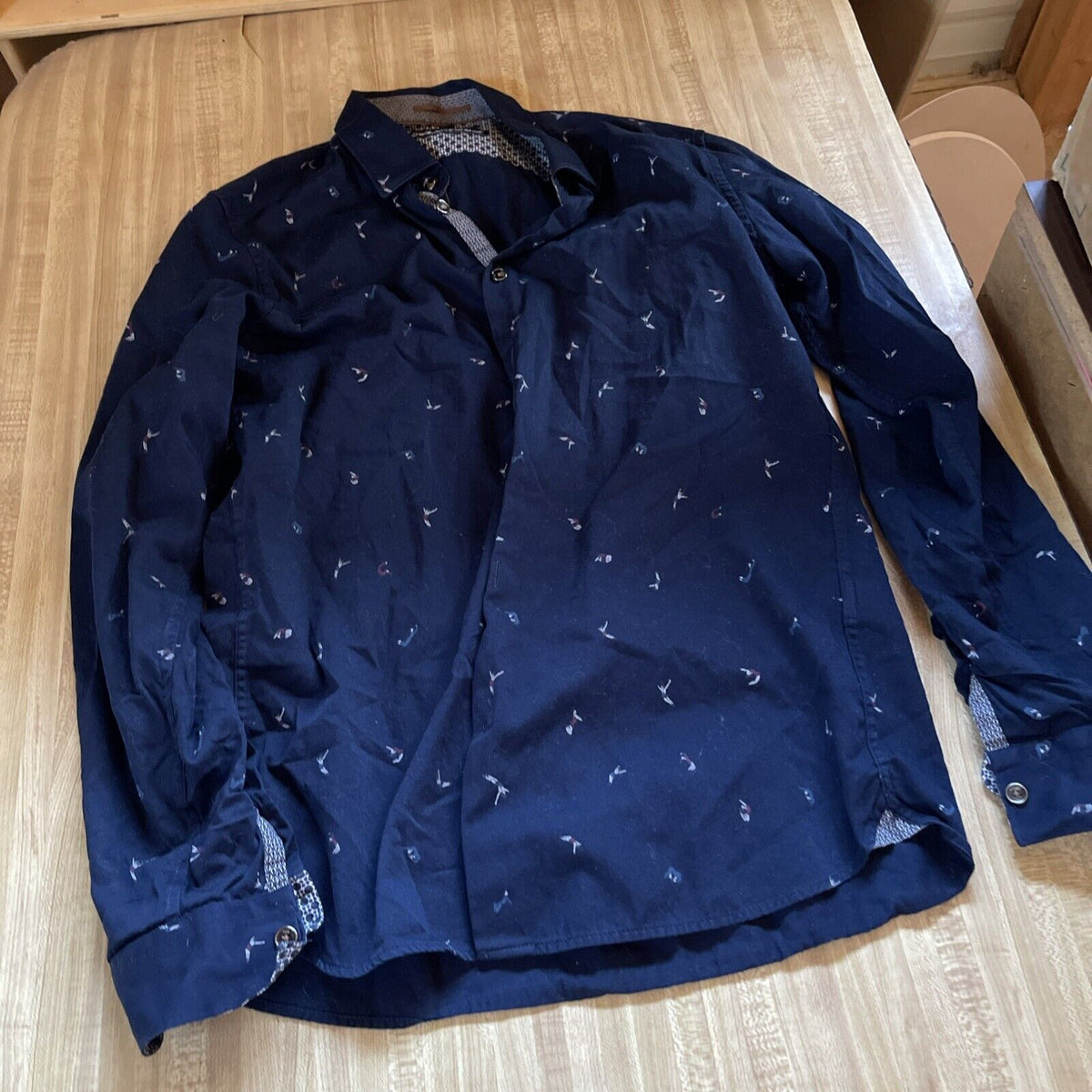 Navy blue Ted Baker men's button up shirt with subtle floral pattern laid flat on wooden surface
