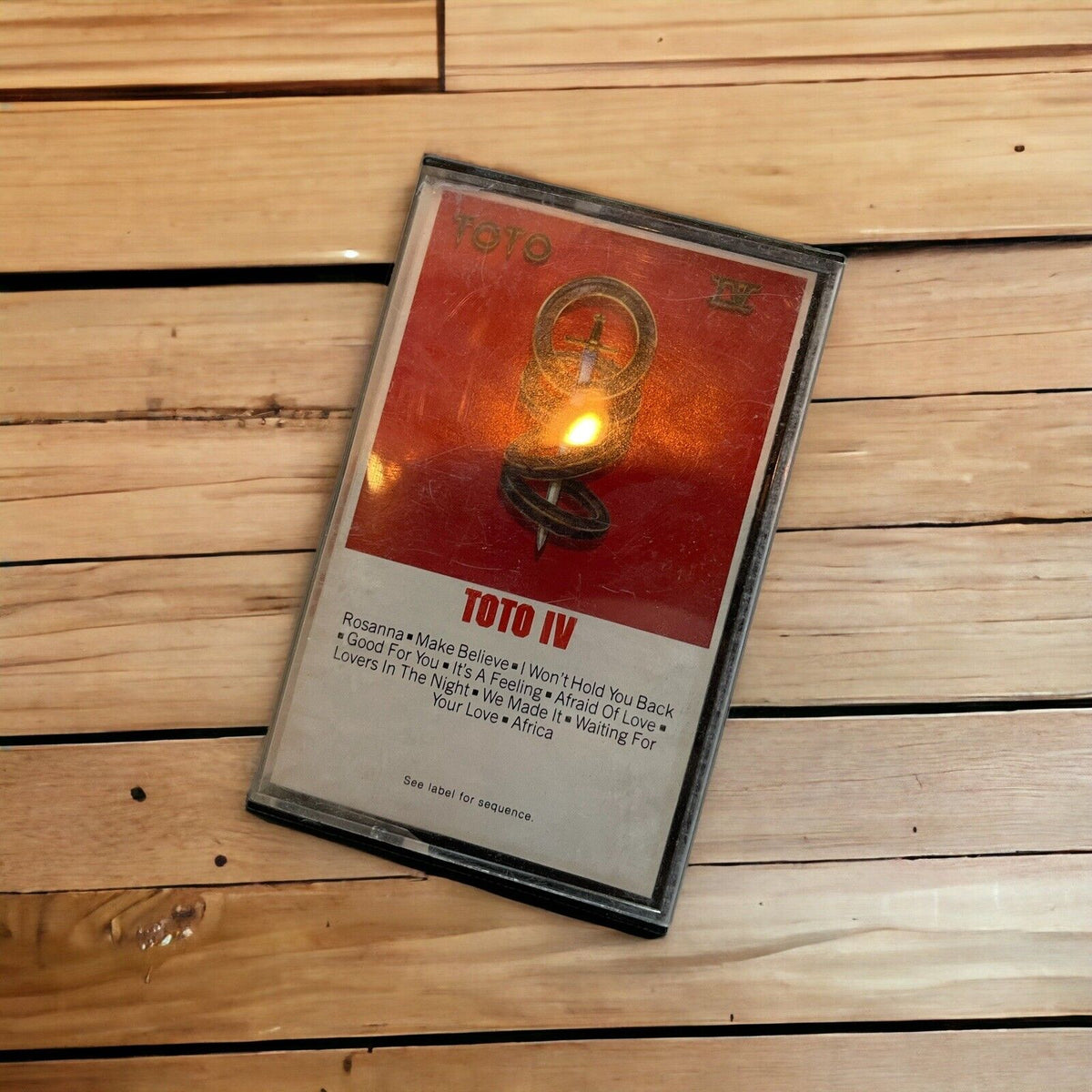 Toto IV cassette tape with classic album cover in protective plastic case on wooden surface