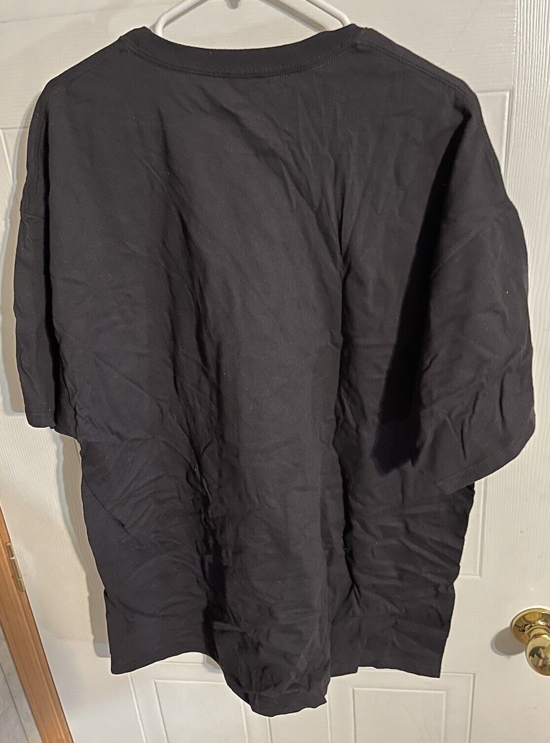 Black USPF powerlifting t shirt XXL hanging on a white hanger against a white door