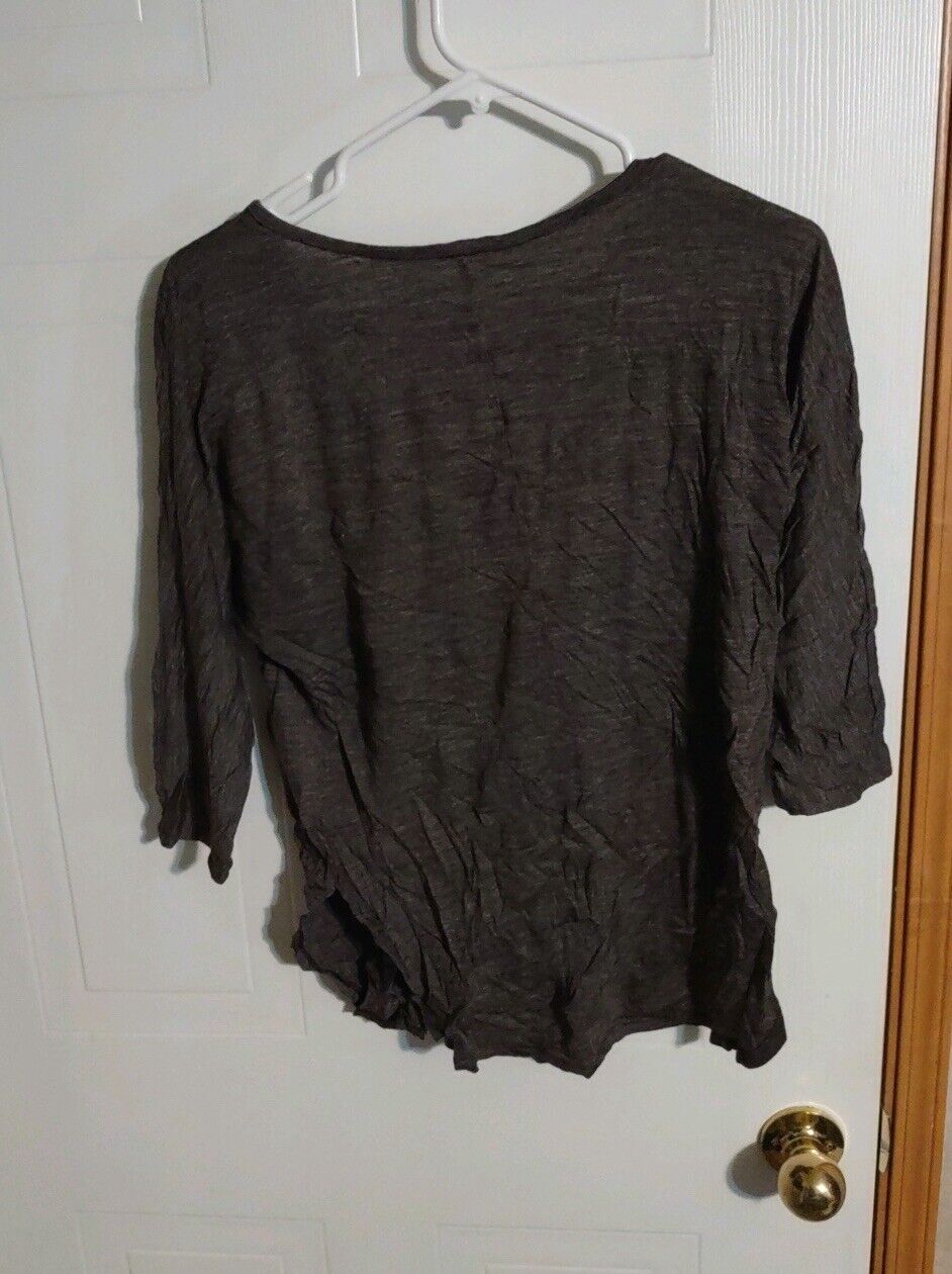 Wrinkled women's casual black blouse hanging on white hanger against white door