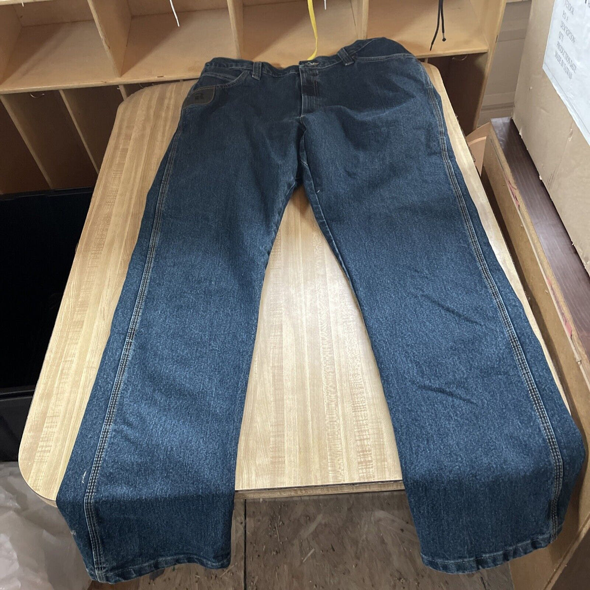 Wrangler Riggs work jeans 38x36 laid flat on wooden table in dark blue denim